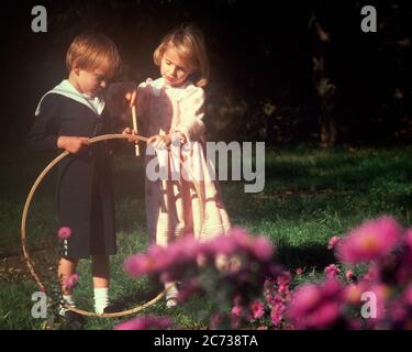 1890s 1970s LITTLE BOY AND GIRL PLAYING TOGETHER WITH HOOP TOY WEARING VICTORIAN STYLE ANTIQUE CLOTHES SOFT FOCUS GRAPHIC EFFECT - kj7578 PHT001 HARS SUBURBAN COLOR SHARING OLD TIME NOSTALGIA BROTHER OLD FASHION SISTER 1 SOFT JUVENILE STYLE HOOP BALANCE TEAMWORK COMPETITION FAMILIES JOY LIFESTYLE SAILOR CELEBRATION FEMALES BROTHERS HEALTHINESS HOME LIFE COPY SPACE PEOPLE CHILDREN FRIENDSHIP FULL-LENGTH PERSONS CARING MALES SERENITY SIBLINGS CONFIDENCE FOCUS SISTERS LINEN GOALS HAPPINESS DISCOVERY TURN OF THE 20TH CENTURY AND RECREATION SIBLING CONNECTION CONCEPTUAL STYLISH SOFT FOCUS Stock Photo