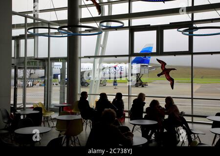 Passengers waiting for departure in Vagar Airport with an Atlantic Airways airplane on the runway in the background.Faroe Islands.Denmark. Stock Photo