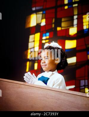 1960s SMILING AFRICAN-AMERICAN LITTLE GIRL IN CHURCH PRAYING WEARING WHITE GLOVES KNEELING STAINED GLASS WINDOW IN BACKGROUND  - kn834 HAR001 HARS RELIGION CELEBRATION FEMALES SUNDAY HOME LIFE COPY SPACE HALF-LENGTH INSPIRATION CARING SPIRITUALITY FREEDOM KNEELING PRETTY HAPPINESS HEAD AND SHOULDERS CHEERFUL AFRICAN-AMERICANS AFRICAN-AMERICAN BLACK ETHNICITY PRIDE IN SMILES CONNECTION CONCEPTUAL JOYFUL STYLISH GROWTH JUVENILES DEVOUT HAR001 OLD FASHIONED AFRICAN AMERICANS Stock Photo