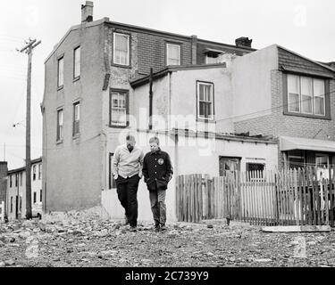 1960s TWO AT ODDS AFRICAN AMERICAN TEENAGE BOYS WALKING THROUGH BLIGHTED POVERTY STRICKEN URBAN AREA NEIGHBORHOOD  - n1963 HAR001 HARS COPY SPACE FRIENDSHIP FULL-LENGTH MALES RISK TEENAGE GIRL TEENAGE BOY SIBLINGS B&W SADNESS TEMPTATION DREAMS NEIGHBORHOOD AFRICAN-AMERICANS AFRICAN-AMERICAN EXTERIOR LOW ANGLE BLACK ETHNICITY DIRECTION PRIDE OPPORTUNITY AREA SIBLING CONCEPTUAL ESCAPE DISADVANTAGED DISAFFECTED DISAPPOINTED DISCONNECTED GROWTH IMPOVERISHED JUVENILES PRE-TEEN PRE-TEEN BOY STRICKEN TOGETHERNESS BLACK AND WHITE DISTRAUGHT HAR001 OLD FASHIONED AFRICAN AMERICANS Stock Photo