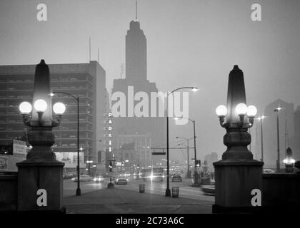 1960s OBELISK LAMPPOSTS ON WACKER DRIVE DOWNTOWN TRAFFIC ON FOGGY NIGHT ALONG CHICAGO RIVER CHICAGO ILLINOIS USA  - r20452 HAR001 HARS MIST VEHICLES EDIFICE ILLINOIS BLACK AND WHITE HAR001 IL LAMPPOSTS MIDWEST MIDWESTERN OBELISK OLD FASHIONED Stock Photo