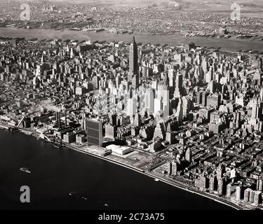 1950s AERIAL VIEW OF ISLAND OF MANHATTAN MIDTOWN NEW YORK CITY VIEW FROM EAST RIVER TO HUDSON RIVER AND NEW JERSEY - r3357 KRU001 HARS REAL ESTATE NEW YORK STRUCTURES CITIES EDIFICE NEW JERSEY NEW YORK CITY METROPOLIS AERIAL VIEW BLACK AND WHITE EAST RIVER EMPIRE STATE BUILDING HUDSON RIVER OLD FASHIONED RIVERS SKYSCRAPERS UNITED NATIONS Stock Photo