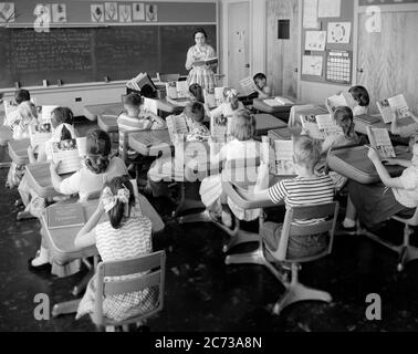 1950s 1960s ELEMENTARY SCHOOL CLASSROOM TEACHER WOMAN AND STUDENTS READING FROM OPEN TEXTBOOKS LEARNING BLACKBOARD DESKS - s12003 HEL001 HARS COPY SPACE HALF-LENGTH LADIES PERSONS INSPIRATION MALES MIDDLE-AGED B&W DESKS SCHOOLS GRADE HIGH ANGLE DISCOVERY AND INSTRUCTOR OCCUPATIONS PRIMARY TEXTBOOKS EDUCATOR COMMUNICATE COOPERATION EDUCATING EDUCATORS GRADE SCHOOL GROWTH INSTRUCTORS JUVENILES MID-ADULT WOMAN PRE-TEEN PRE-TEEN BOY PRE-TEEN GIRL SCHOOL TEACHES TOGETHERNESS BLACK AND WHITE CAUCASIAN ETHNICITY OLD FASHIONED Stock Photo