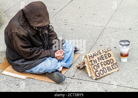 San Francisco California,Chinatown,Grant Street,homeless,poverty,beggar,vagrant,charity,sign,AIDS,hungry,hooded jacket,sitting on ground,cardboard,pap Stock Photo