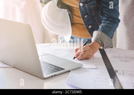 Engineer or architect holding pen with drawings in construction on blueprints in office. Engineering and construction concept. Stock Photo