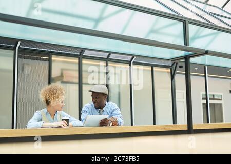 Businessman discussing some work with businesswoman while she drinking coffee they standing at office building Stock Photo