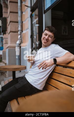Brunette man in street cafe drinks coffee. Stock Photo