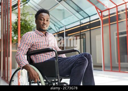 Portrait of African young disabled man sitting in wheelchair at office building Stock Photo