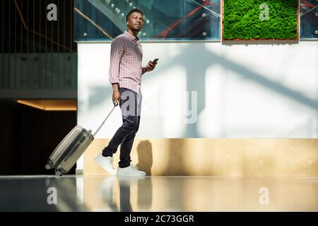 African young businessman walking along the corridor with luggage at the airport he has a business trip Stock Photo