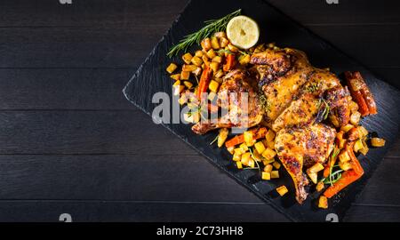 Butterflied grilled whole chicken with roasted vegetables and potatoes. Roadkill chicken style with herbs and lemon. Stock Photo