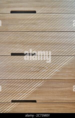 Wooden cupboard with drawers in daylight. Modern wooden furniture. Wooden texture. Close-up Stock Photo