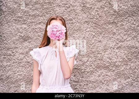 Girl hide face. Pink peony faceless woman. Flower summer Stock Photo