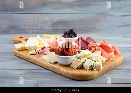 Italian antipasto. Antipasti board with ham, salsami, prosciutto, parmesan, blue cheese and olives. Stock Photo