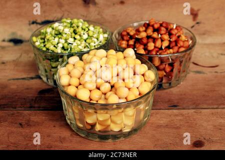 Collection of legumes (chickpeas, green peas, green mung beans, Red Kidney, Dry peas)in different bowls isolated on wooden background. Stock Photo
