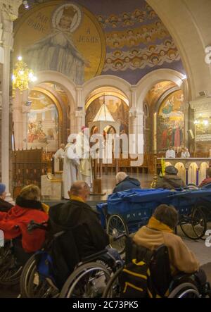 Apr 28. 2014 Lourdes France  Bishop prays for the healing of sick people in wheelchairs at Rosary Basilica. Stock Photo