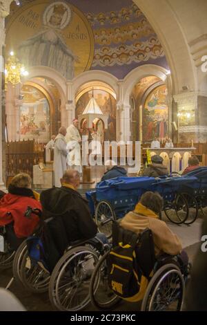 Apr 28. 2014 Lourdes France Bishop prays for the healing of sick people in wheelchairs at Rosary Basilica. Stock Photo