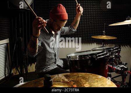 energetic caucasian drummer man professionally play on drums, he enjoy performing music in studio, preparing for concert. rock and roll, music, instru Stock Photo