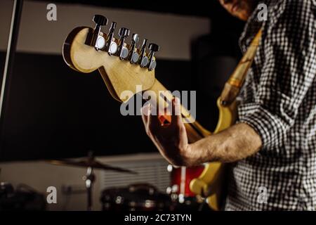 close-up photo of young man holding electric guitar, talented musician perform music in studio, preparing for concert Stock Photo