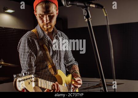 rock and roll. professional musician play electric guitar in studio. handsome guy with beard practicing in recording studio Stock Photo