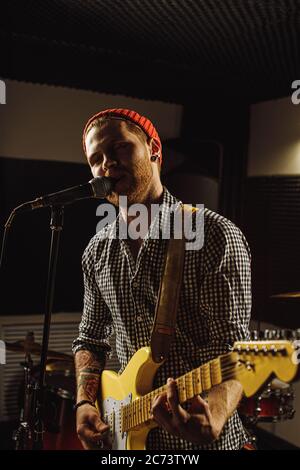 young caucasian rock musician play on electric guitar, man keen on rock music, perform music in recording studio. instruments, equipment, music concep Stock Photo