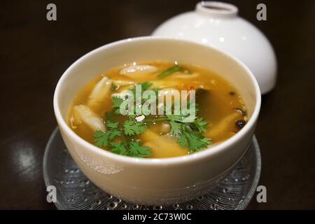 Close up ceramic bowl of Tom Yum- Thai style spicy broth soup made of chili paste and mushroom Stock Photo
