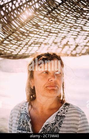 Adult Caucasian Woman Relaxed Posing Under Beach Umbrella On Sunset. Vacation On Sea Ocean Stock Photo