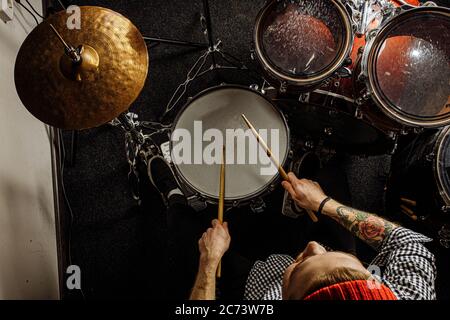 top view on handsome talented guy playing on drums, caucasian young man keen on music, preparing for concert, rock and roll performer. music, instrume Stock Photo