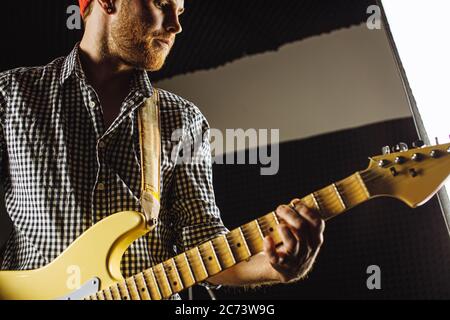 handsome caucasian guy enjoy playing electric guitar in recording studio, he is practicing before concert. professional musician perform music. rock Stock Photo