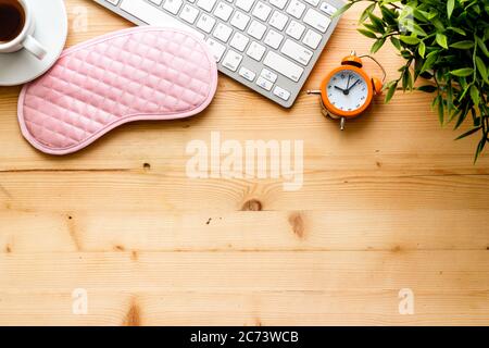 Hard exhausing work concept. Sleep mask on wooden office desk top view copyspace Stock Photo