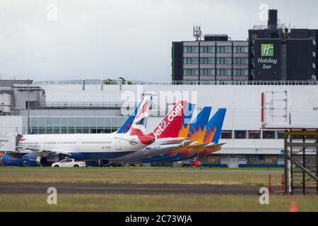 Glasgow, Scotland, UK. 14th July, 2020. Pictured: A row of Jet2 Holidays Airlines planes sit on the tarmac at Glasgow International Airport due to the coronavirus (COVID19) pandemic. Jet2 have said, “Because of the travel restrictions that are still in place to Spain as a result of this week's announcement by the Scottish government, we have taken the decision to recommence our flights and holidays programmes from Edinburgh and Glasgow Airports to Mainland Spain, the Balearic Islands and the Canary Islands on 25 July 2020.” Credit: Colin Fisher/Alamy Live News Stock Photo