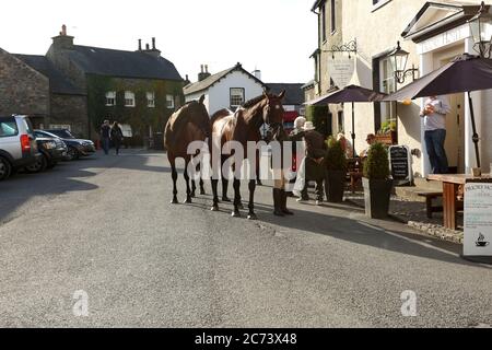 Race horses being lead by a woman jockey in Cartmel village, Cumbria, England.The photo was taken on 13th September, 2015 Stock Photo