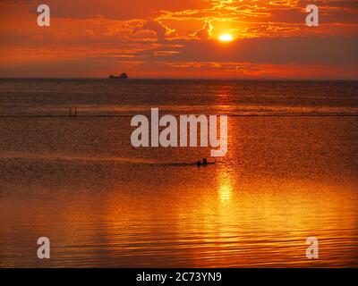 Two swimmers at Sunset in the Walpole Bay Tidal Pool, Margate, Kent, UK Stock Photo