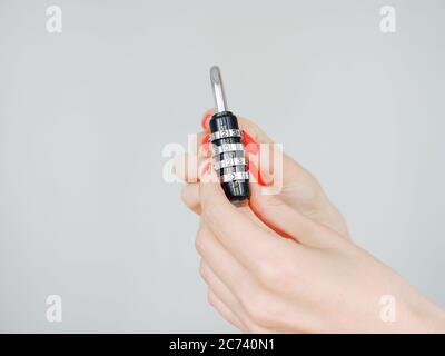 Female hands with red manicured nails holds a black padlock with the numbers 2020 Stock Photo