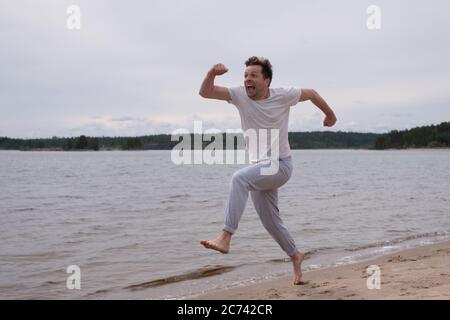 Man in fitness clothing running along sandy beach Stock Photo