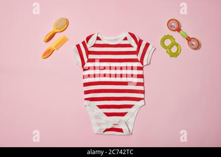 Baby fashion concept on a pink background. Striped bodysuit, scallop and beanbag. Stock Photo
