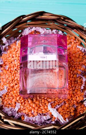 Transparent pink bottle of perfume in the basket of lentils. Stock Photo