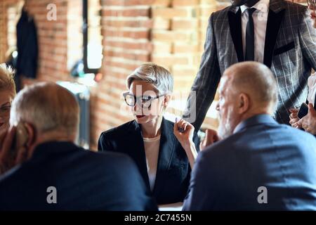 Focused on blonde caucasian woman in glasses between backs of two men Stock Photo