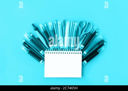 Back to school background with opened notepad and variety of school supplies in trendy aqua color. Flat lay. Close-up. Copy space. Mockup for your des Stock Photo