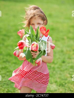 Girl in the park with a bouquet of red tulips in her hands Stock Photo