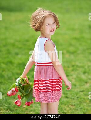 Happy girl with a bouquet of red tulips in the garden Stock Photo