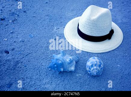 Pop art surreal style white straw hat on azure blue sand beach and seashells Stock Photo