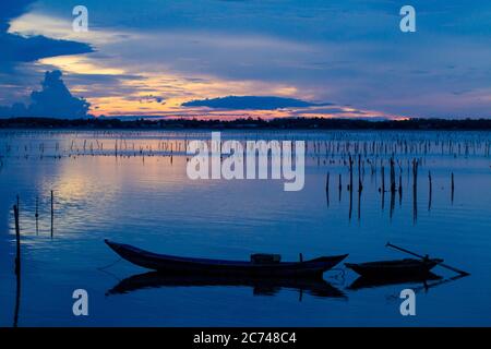 Wonderful landscape at Lap An lagoon, Vietnam with the floating house, wooden boat and amazing colorful sky of sunrise. Stock Photo