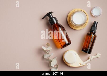 Bathroom cosmetics and accessories on brown background. Flat lay, top view. Pump bottle, cosmetic spray lotion, candles, body clean brush, eucalyptus Stock Photo