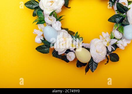 A colorful Easter egg wreath isolated over yellow background. Easter holiday concept with copyspace for text. Stock Photo