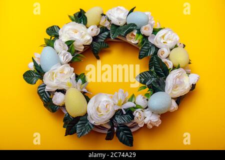 A colorful Easter egg wreath isolated over yellow background. Easter holiday concept with copyspace for text. Stock Photo