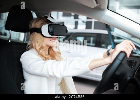 Pretty woman sitting in a car in 3D glasses of virtual reality Stock Photo