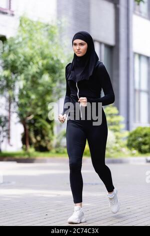 young arabian sportswoman in hijab and sportswear running outside Stock Photo