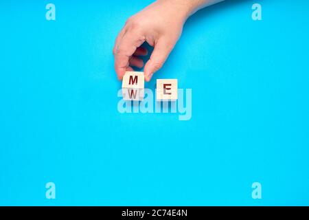 Teamwork concept. Hand turns dice and changes the word ME to WE. Solidarity vs Individualism Concept Stock Photo