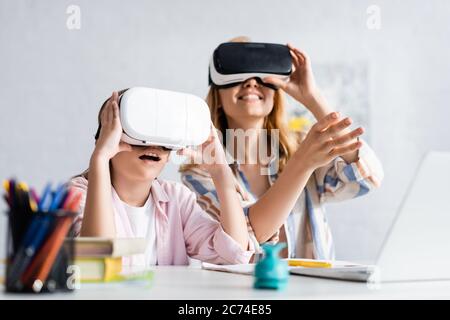 Selective focus of excited kid using vr headset near mother during online education Stock Photo