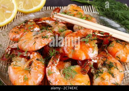 fried king prawns in a plate on a bamboo mat, lemon, dill, close-up Stock Photo